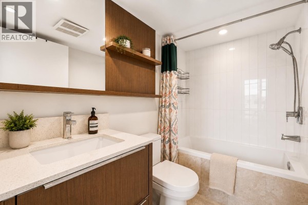 Bathroom with white tiled shower-tub, wooden vanity, and quartz countertop sink. - 705 538 W 7th Avenue, Vancouver