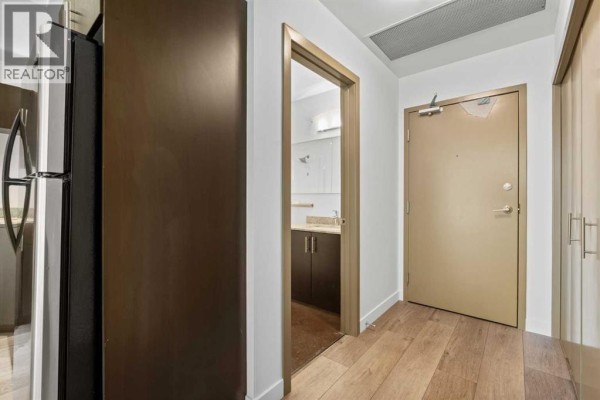 Interior hallway with a metal-clad door, beige closet doors, and polished concrete floors. - 706, 135 13 Avenue Sw, Calgary