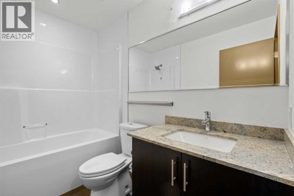Open-concept living area and kitchen with dark wood cabinets, stainless steel appliances, and polished concrete floors. - 706, 135 13 Avenue Sw, Calgary