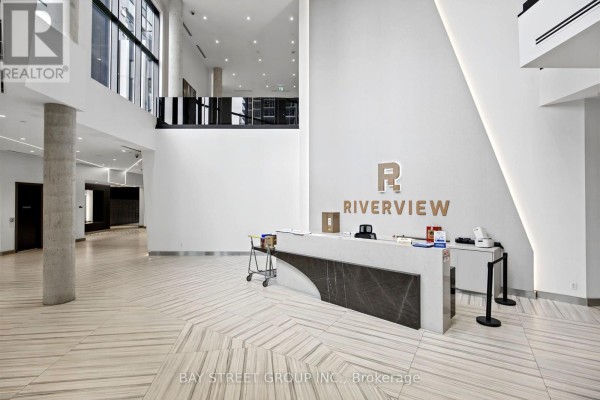 Spacious, white lobby with a reception desk, marble counter, and patterned floor. - 706 - 18 Water Walk Drive, Markham