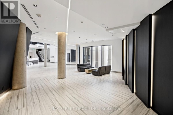 Modern lobby with concrete columns, seating area, and dark accent walls. - 706 - 18 Water Walk Drive, Markham