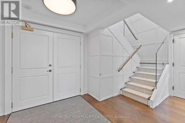 Double white doors open to a foyer with a staircase featuring a glass railing and carpeted steps. - 706 - 1818 Bayview Avenue, Toronto