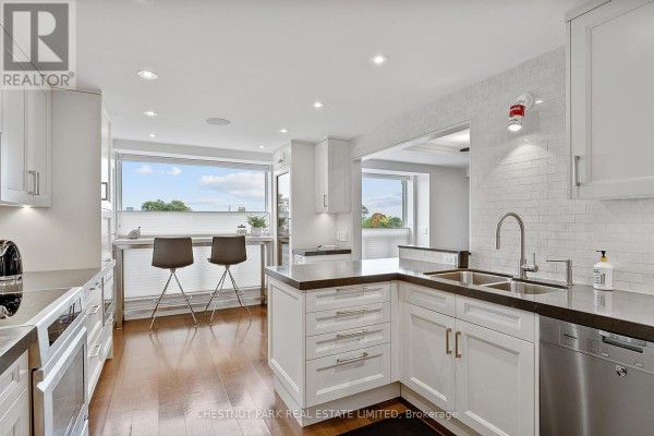 Expansive white kitchen with dark counters, subway tile backsplash, stainless steel appliances, and a dinette area. - 706 - 1818 Bayview Avenue, Toronto