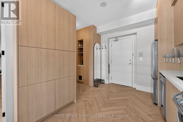 Entrance hallway with ample built-in light wood storage and herringbone hardwood floors. - 706 - 33 Shore Breeze Drive, Toronto