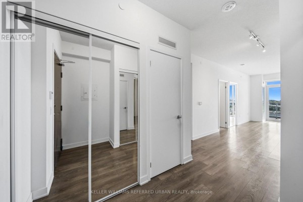 Apartment hallway with mirrored closet doors, white walls, and light wood laminate flooring. - 706 - 38 Honeycrisp Crescent, Vaughan