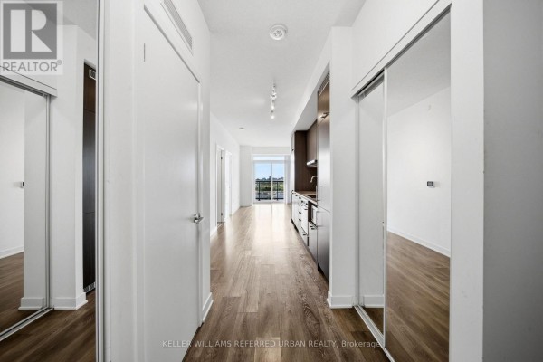 Apartment hallway with mirrored closet doors, light wood floors, and glimpses of kitchen. - 706 - 38 Honeycrisp Crescent, Vaughan