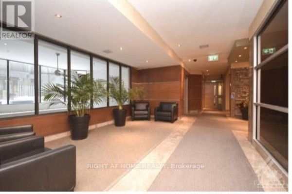 Building lobby with dark leather seating, potted plants, and hallway leading to elevators. - 706 - 470 Laurier Avenue W, Ottawa