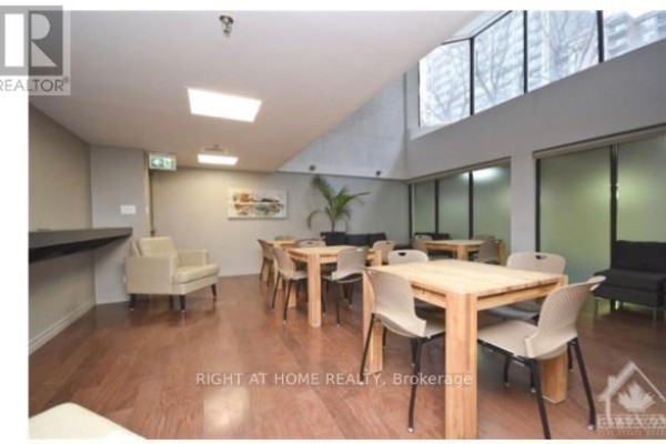 Communal lounge with wooden tables, chairs, seating areas, and large windows. - 706 - 470 Laurier Avenue W, Ottawa