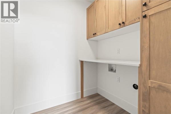 Laundry room with light wood cabinets, a white countertop, and connections for washer and dryer. - 7060 Manning Place, Vernon
