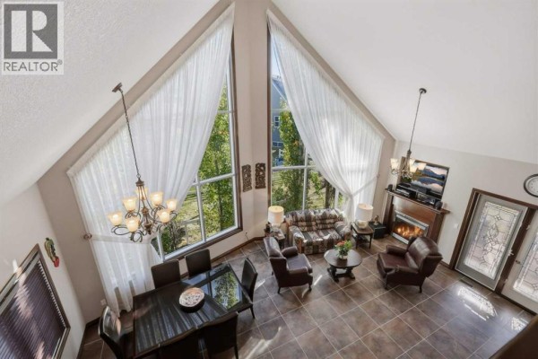 High-angle view of an open-concept living and dining area with vaulted ceilings and large windows. - 7062, 35468 Range Road 30, Rural Red Deer County