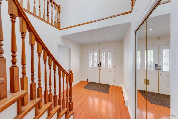 Entrance hallway with double glass doors and a wooden staircase. - 7069 144 Street, Surrey
