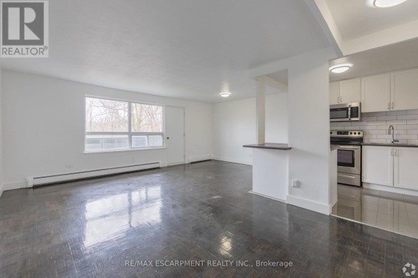 Living room with dark hardwood floors and view of an adjacent kitchen. - 707 - 285 Erb Street W, Waterloo