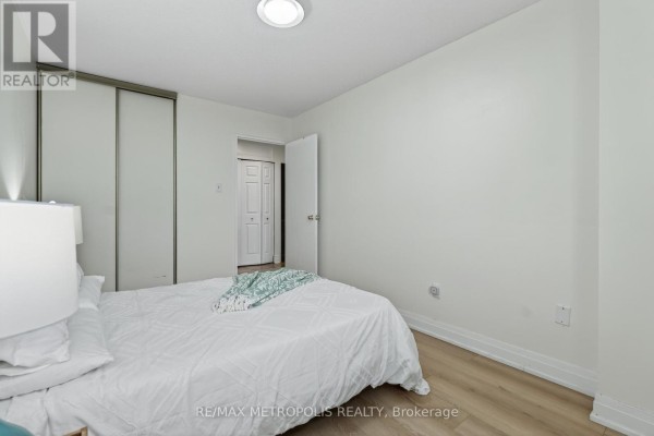 Bedroom with a bed, white bedding, and sliding door closet, looking towards an open doorway. - 707 - 44 Falby Court, Ajax