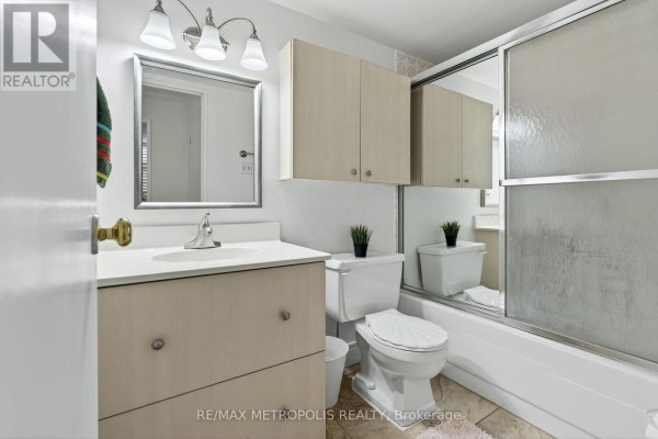 Bathroom with vanity, sink, toilet, and bathtub with a sliding glass shower door. - 707 - 44 Falby Court, Ajax