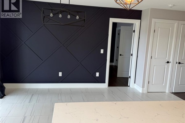 Dining area with a dark blue accent wall with geometric paneling and white double doors. - 707 Faleria Street, Lakeshore