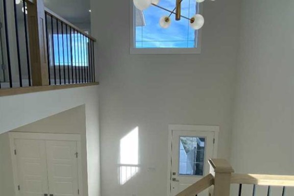 View of the entryway from above, showing the staircase, double doors, and a large window above the front door. - 707 Mandalay Avenue Nw, Carstairs