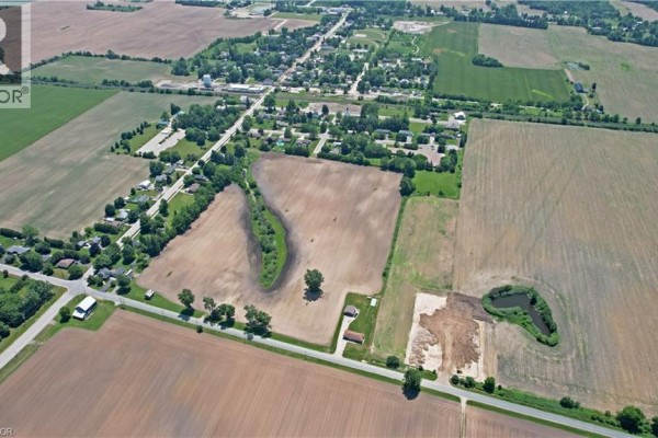 Aerial view showing houses and farm fields surrounding the property, with a distant view of a small town. - 707016 Township Road 2 Road, Princeton