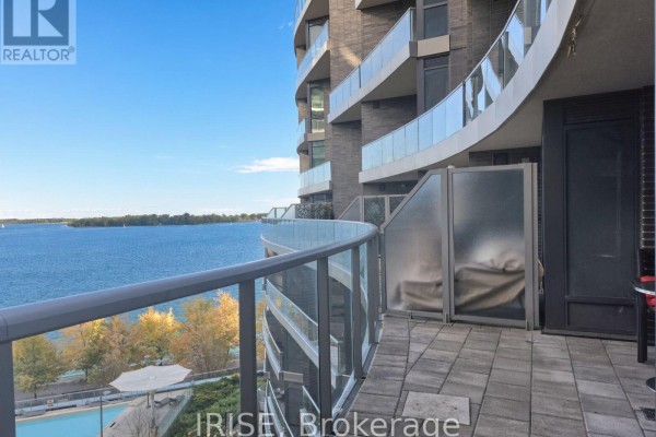 Balcony with grey tile flooring, glass railings, and a view of the lake. - 708 - 1 Edgewater Drive, Toronto