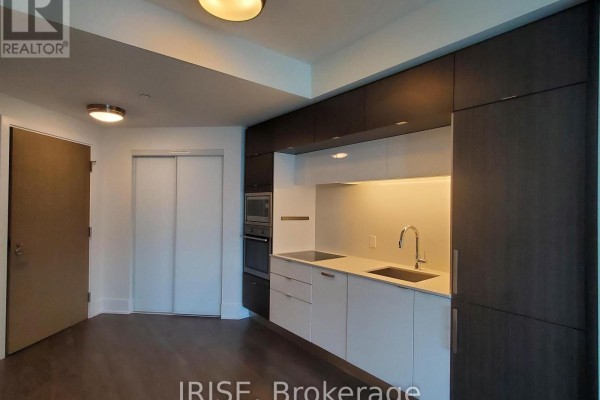 Open concept kitchen with white counters, dark wood cabinets, and stainless steel appliances. - 708 - 1 Edgewater Drive, Toronto