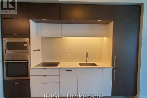 Modern kitchen with white cabinetry, integrated stainless steel appliances, and pendant lighting. - 708 - 1 Edgewater Drive, Toronto