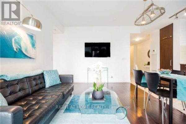 Living and dining area with a black leather sofa, glass coffee table, and dining set. - 708 - 14 York Street, Toronto