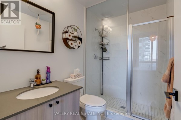 Bathroom with a modern vanity, toilet, and a glass-enclosed shower with white tile. - 708 - 1480 Bayly Street, Pickering