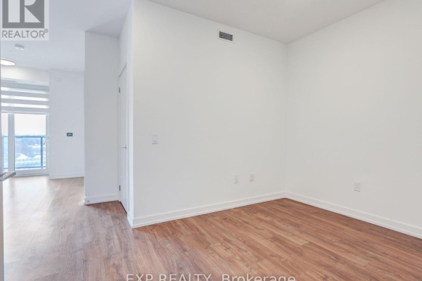 Empty room with hardwood flooring and white walls, ready for personalization - 708 - 15 Wellington Street S, Kitchener