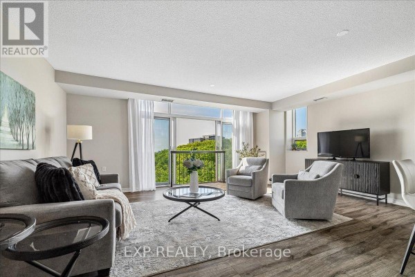 Living room with grey sofa, two armchairs, coffee table, and a tv on a dark cabinet. - 708 - 200 Burnhamthorpe Road E, Mississauga