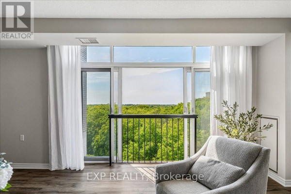 Balcony view from apartment with black railing, white curtains, and a lush green tree canopy. - 708 - 200 Burnhamthorpe Road E, Mississauga