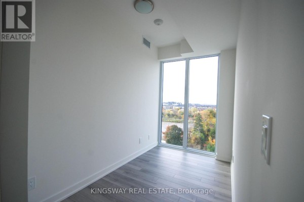 Empty room with a large window overlooking trees and distant buildings. - 708 - 3071 Trafalgar Road, Oakville