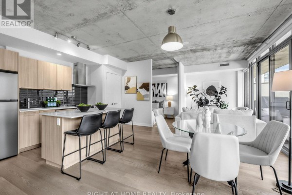 Open concept kitchen with island, bar stools, dining area, and living room beyond. - 708 - 650 King Street West Street W, Toronto