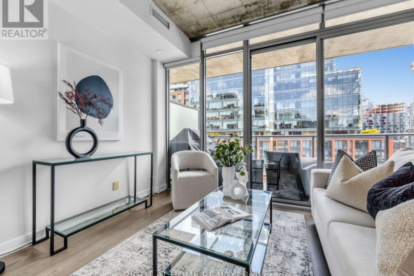 Living room corner with armchair, console table, artwork, and city view. - 708 - 650 King Street West Street W, Toronto