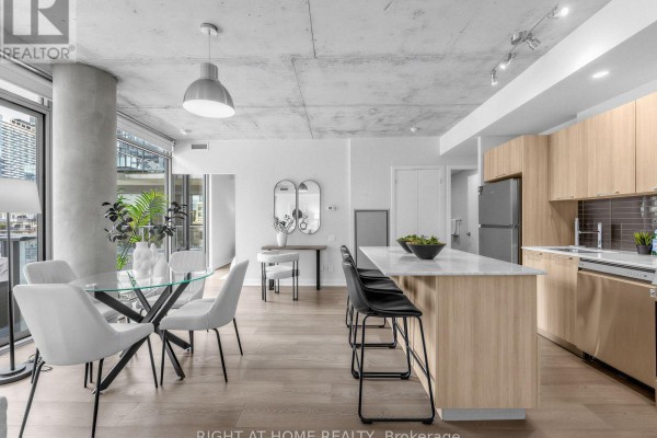 Kitchen island with bar stools, dining table with chairs, and view of living area. - 708 - 650 King Street West Street W, Toronto