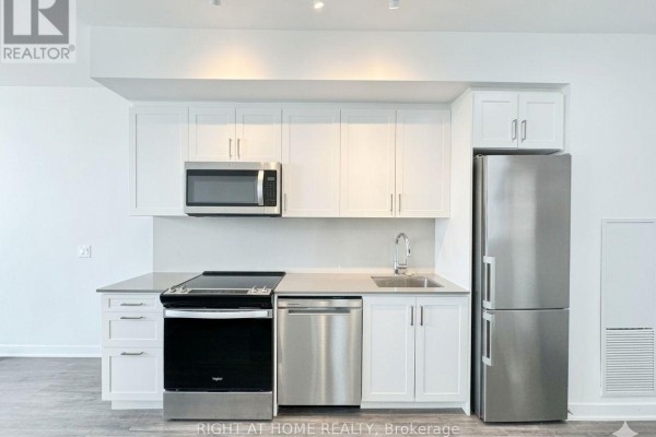 Modern kitchen with white cabinetry, stainless steel appliances, and grey countertops. - 708 - 681 Yonge Street, Barrie