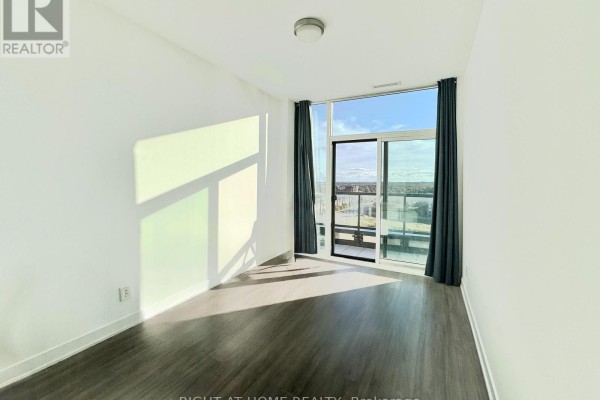 Bright living space with floor-to-ceiling windows, dark curtains, and balcony access. - 708 - 681 Yonge Street, Barrie