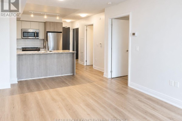 Open concept living area with light wood flooring, granite island, and stainless steel kitchen appliances. - 708 - 9 Valhalla Inn Road, Toronto