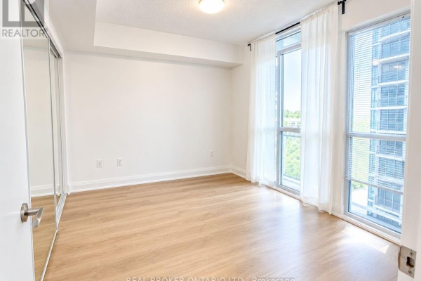 Bedroom with mirrored closet doors, light wood flooring, and large windows with city views. - 708 - 9 Valhalla Inn Road, Toronto