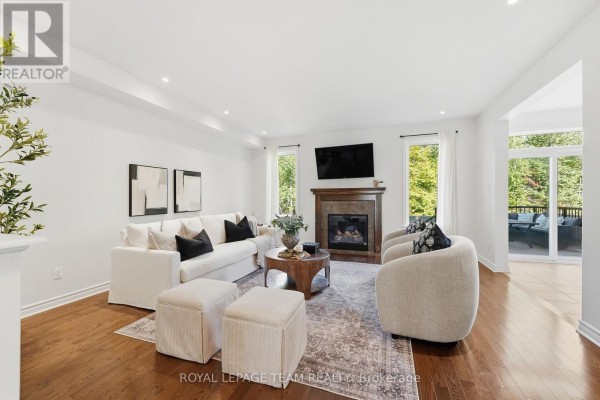 Living room with a white sectional sofa, fireplace, television, and access to an outdoor patio. - 708 Eagle Crest Heights, Ottawa