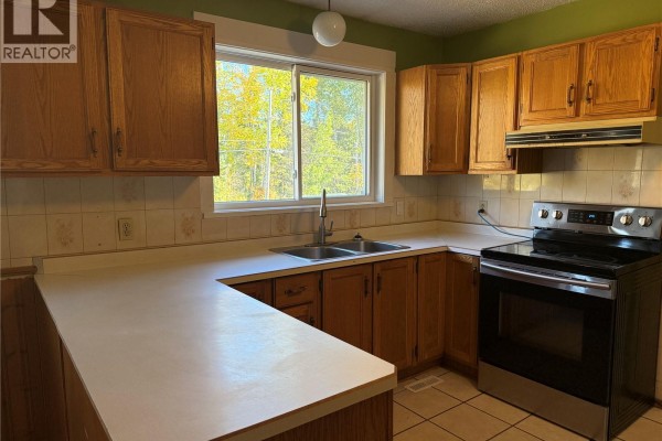 Kitchen with light wood cabinets, white countertops, and a stainless steel sink. - 708 Studer Street, La Ronge