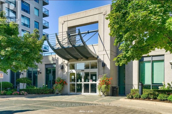 Building entrance with glass doors, stone facade, and potted plants. - 709 - 28 Harrison Garden Boulevard, Toronto