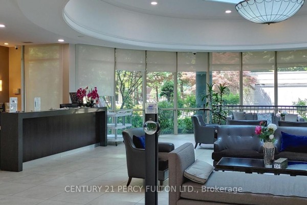 Lobby reception desk, seating area, and large windows overlooking greenery. - 709 - 28 Harrison Garden Boulevard, Toronto
