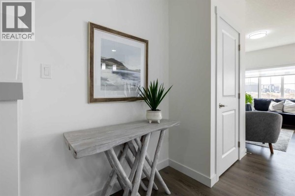 Hallway with a decorative console table and framed artwork, leading to living area - 709 Clearview Green, Chestermere