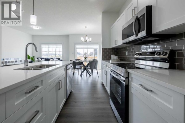 View of kitchen and dining area with stainless steel appliances and large windows for natural light - 709 Clearview Green, Chestermere