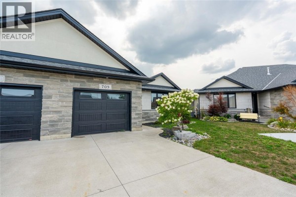 Side view of the detached house, showing the double garage and stone exterior. - 709 Ferdinands Crescent, Sarnia