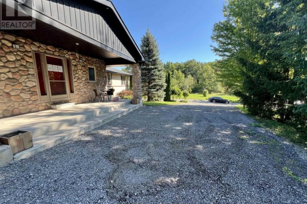 View of driveway from covered front porch with stone columns and trees. - 709 Roland Road, Pelham