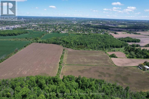Expansive aerial view of farmland with scattered trees and a distant town. - 7096 Fife Road, Guelph/eramosa
