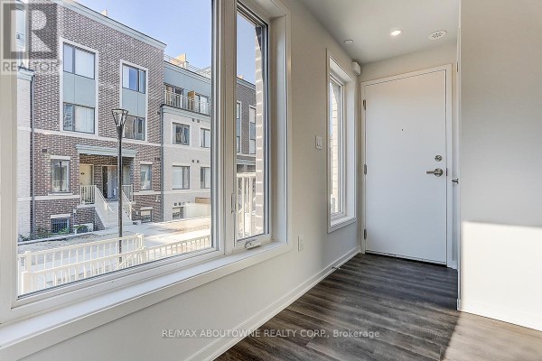 Entranceway with large windows overlooking the street, white door, and grey wood-look flooring. - 71 - 5 William Jackson Way, Toronto