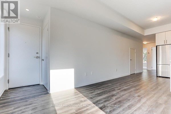 Bright living area with white walls, grey wood-look flooring, and multiple doors. - 71 - 5 William Jackson Way, Toronto