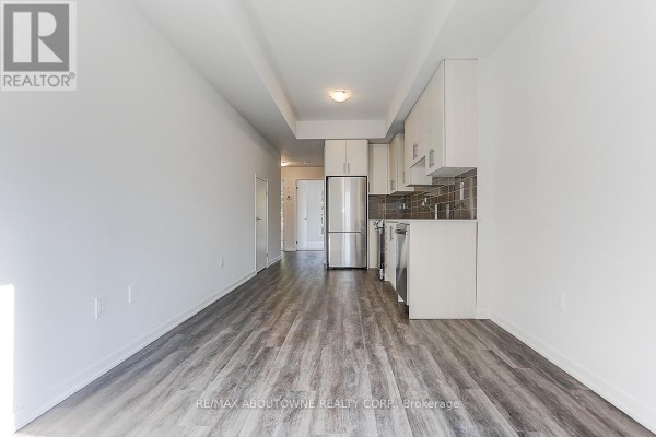 Open concept space with living area and kitchen featuring white cabinets and stainless steel appliances. - 71 - 5 William Jackson Way, Toronto