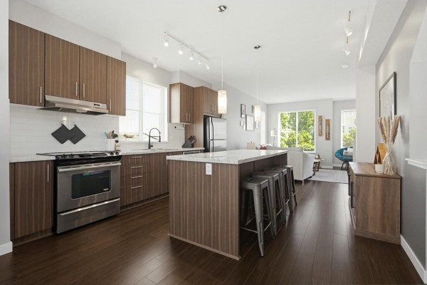 Spacious communal lounge area with a dining table, sofa, chairs, television, and a kitchenette counter. - 71 31032 Westridge Place, Abbotsford